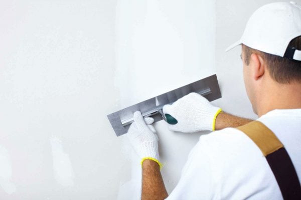 A man is applying finishing putty for painting