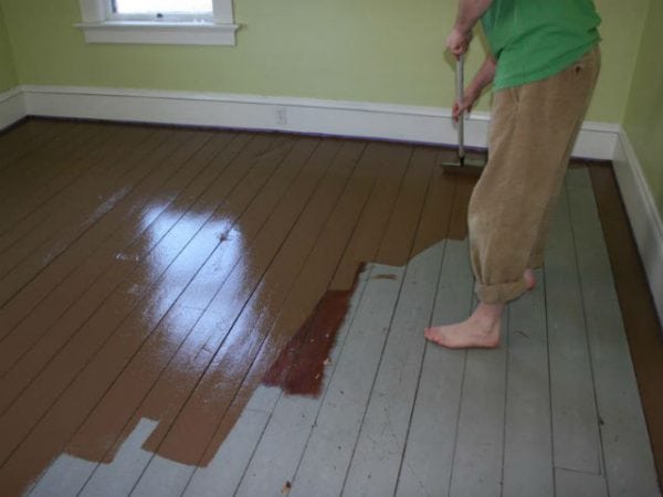 Femme peint un plancher en bois