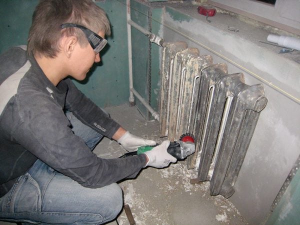 A man removes old paint from metal