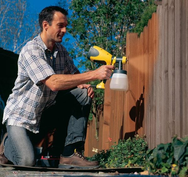 Painting a fence with a spray gun