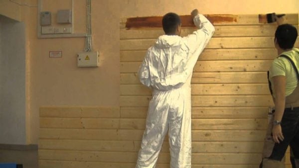 Peindre un mur en bois à l'intérieur d'une maison avec de la peinture