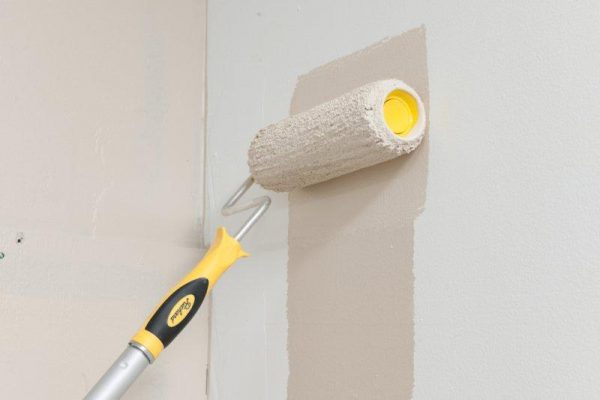 Painting the wall with water-based paint using a roller