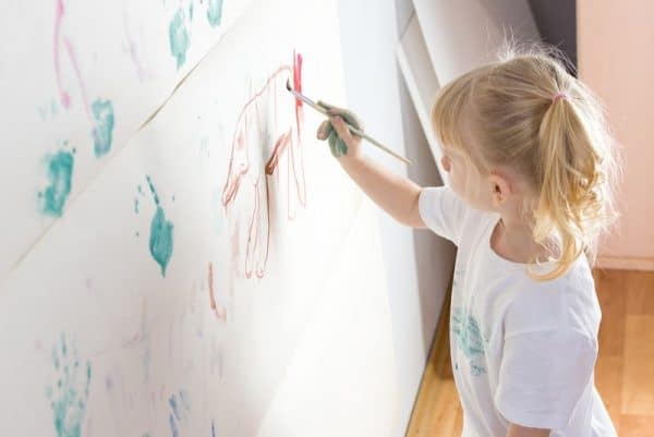 Girl draws on the wallpaper